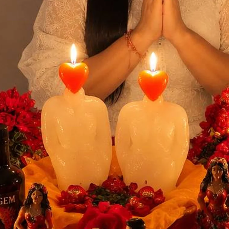 Duas velas brancas com chama em forma de coração sobre o altar de amor, cercadas de rosas vermelhas